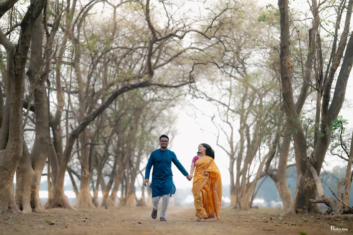 Couple walking hand in hand beneath a tree-lined path
